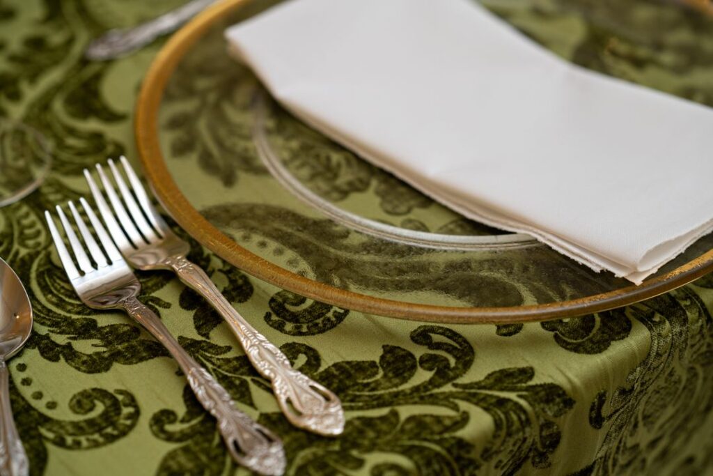 gold rim charger and green damask tablecloth